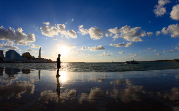 Silhouette of a boy on the seafront at sunset